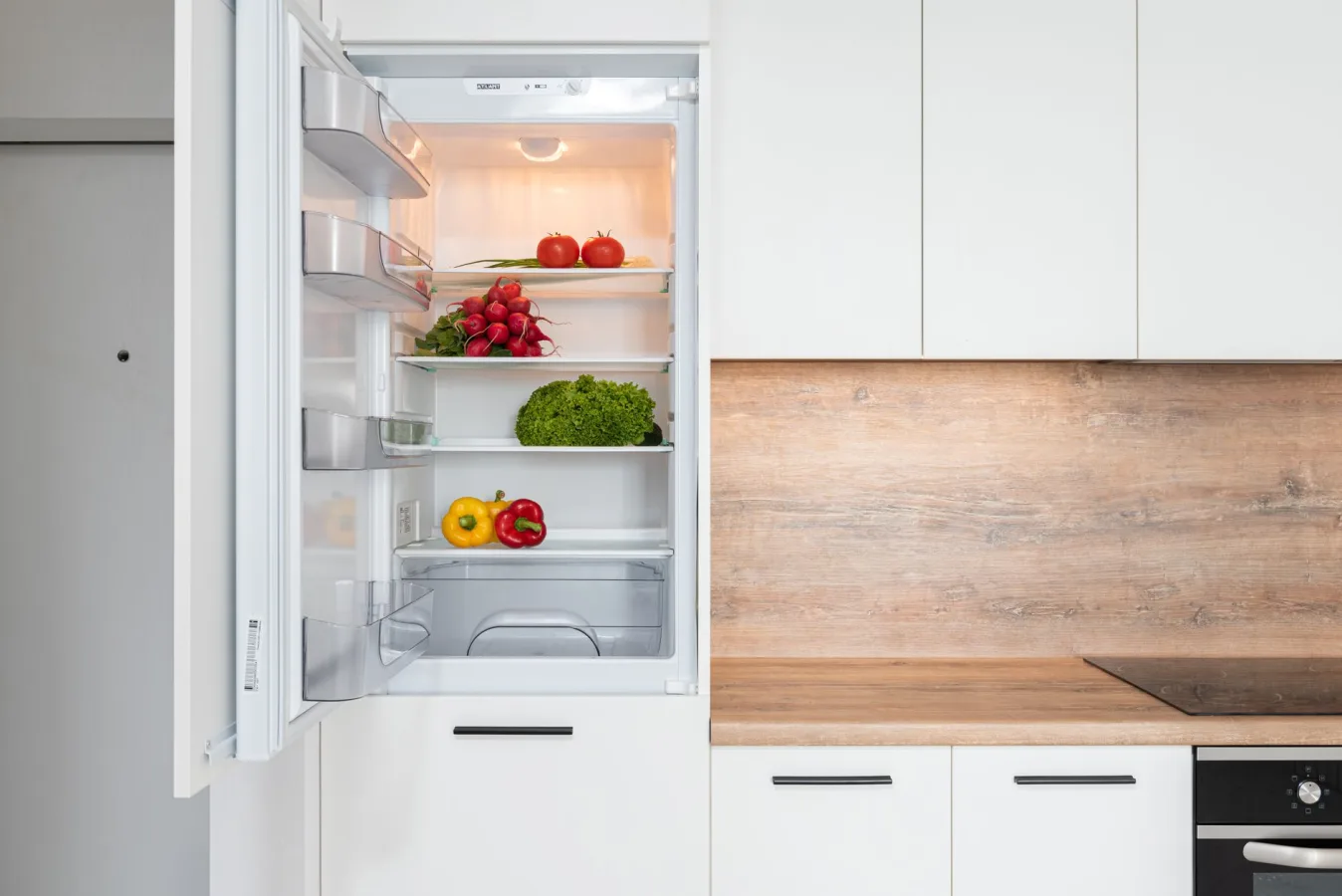 Contemporary kitchen with refrigerator filled with fresh bright tomatoes lettuce and bell