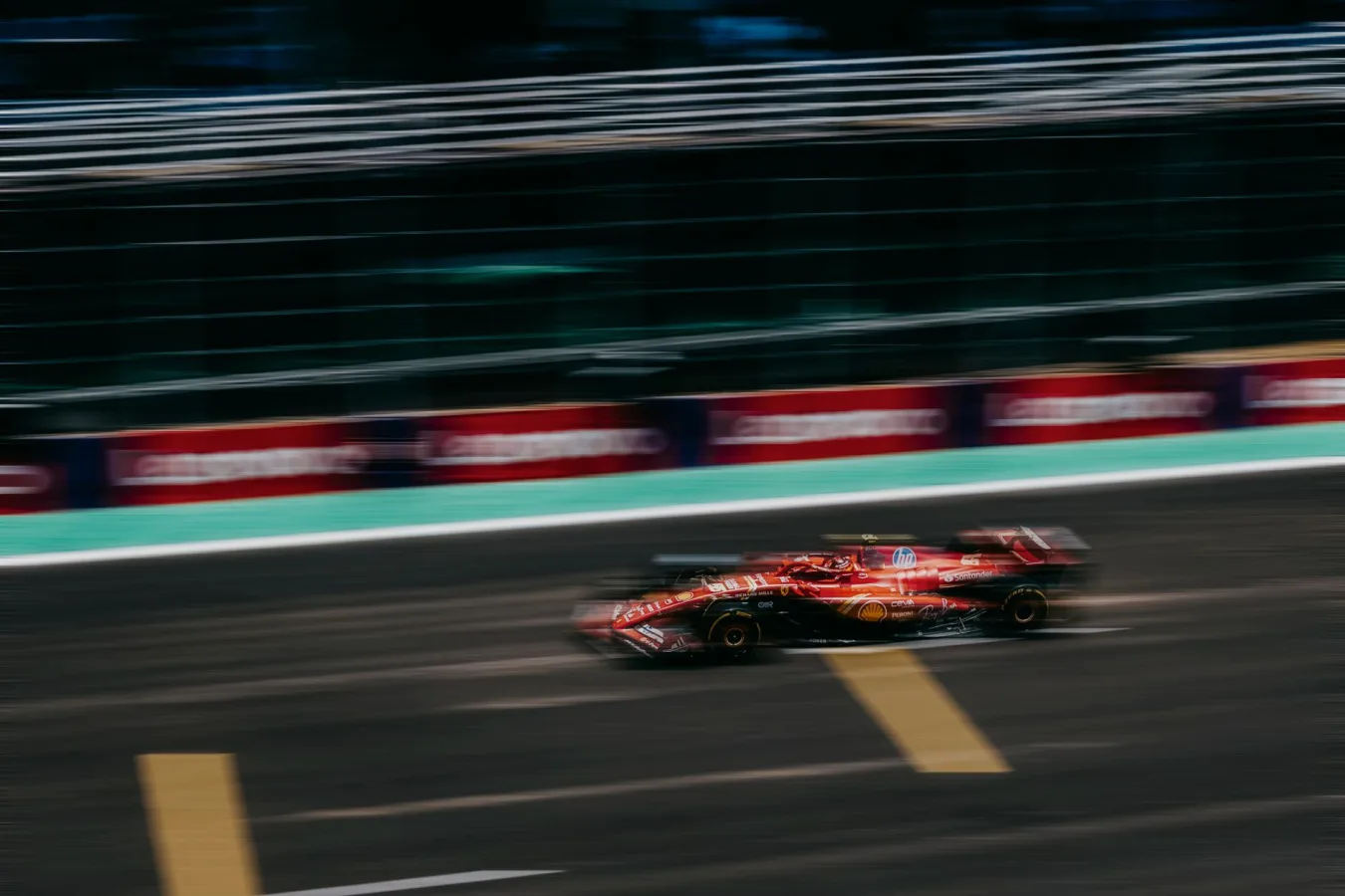 Blurred red racing car speeding on a race track during daytime.