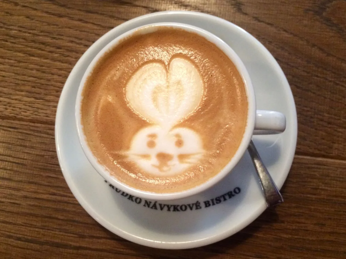 A delightful cup of coffee with rabbit latte art on a wooden table, perfect for a café vib