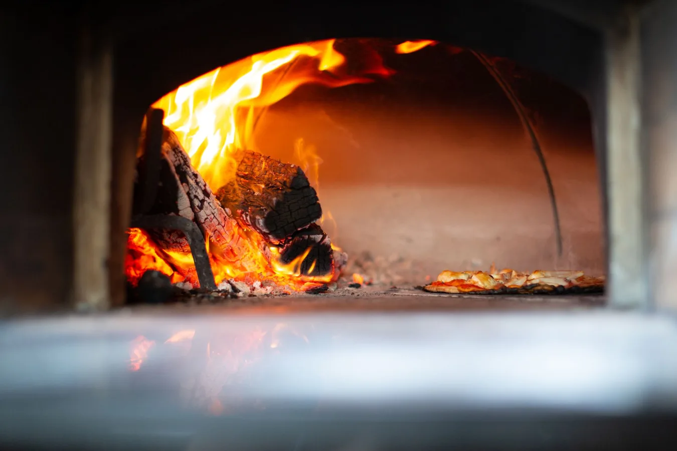 Authentic pizza baking with open flames in a traditional wood-fired oven, creating a rusti