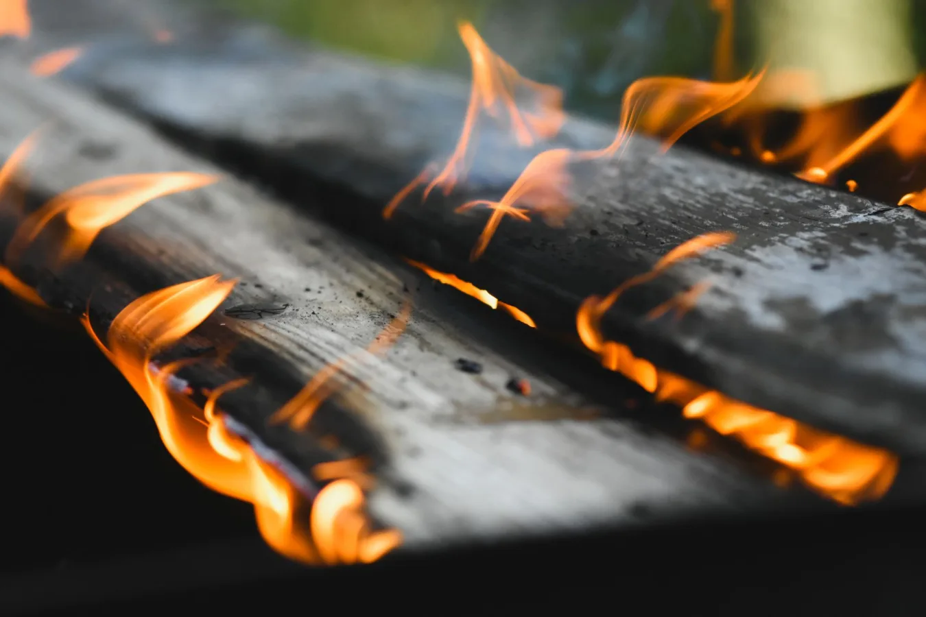 Vivid flames engulf wooden planks in an outdoor fire setting, showcasing warmth and energy