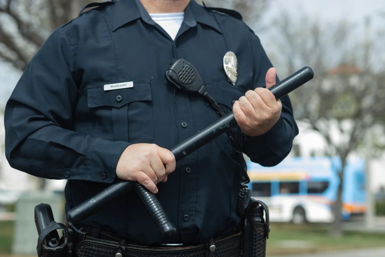 Close-up of a police officer holding a baton outdoors, emphasizing authority and security.