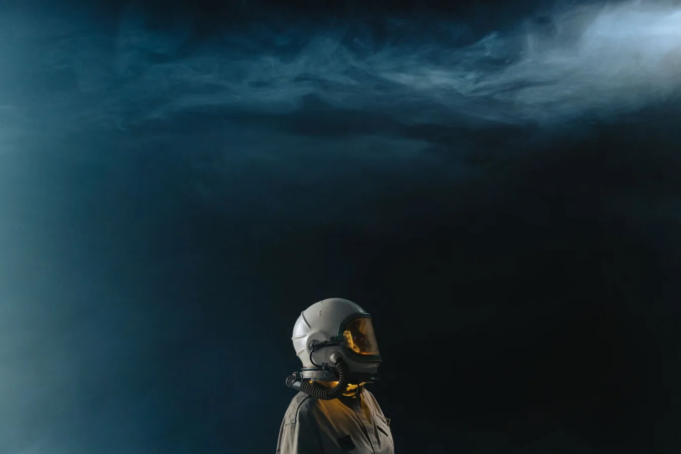 Astronaut in a helmet looks toward the stars in a mysterious space setting.