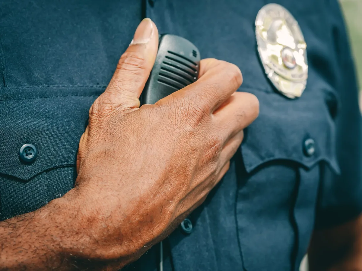 A police officer in uniform holding a radio communicator, showcasing professional authorit