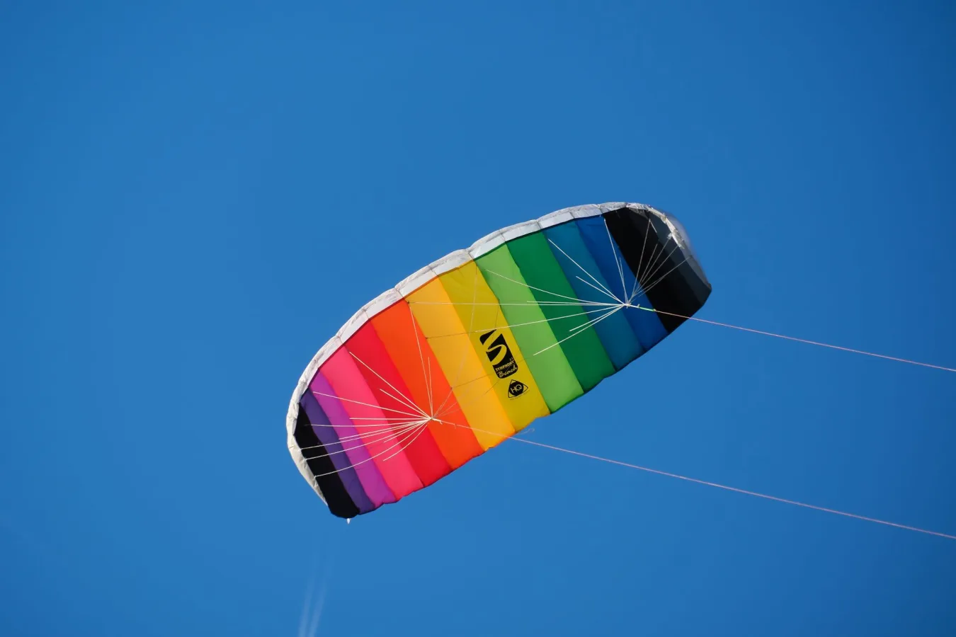 Vibrant rainbow-colored kite soaring high in a clear blue sky, symbolizing freedom and joy