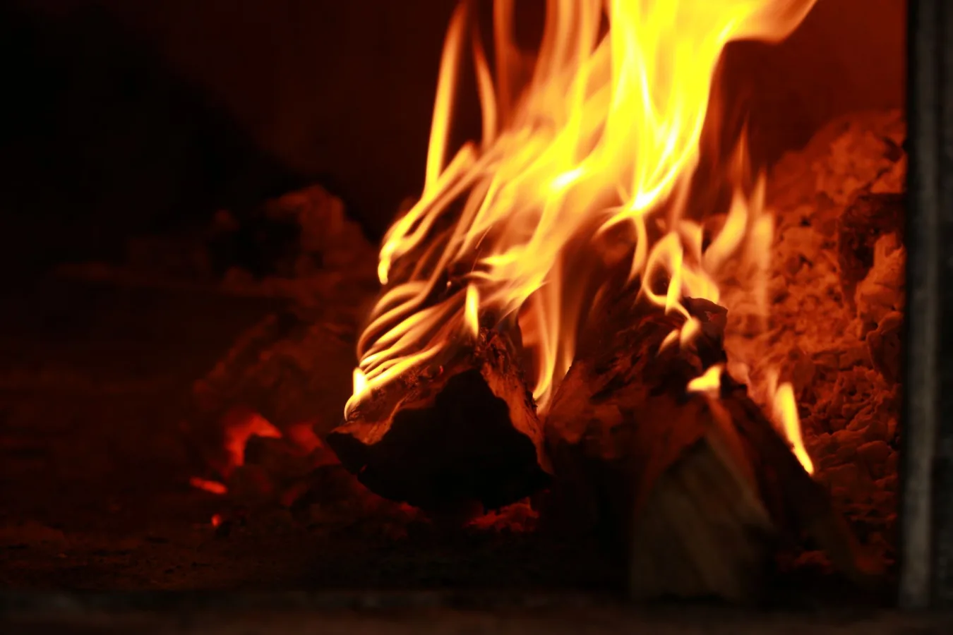 Close-up of firewood burning with bright flames in a wood-fired oven. Perfect for culinary